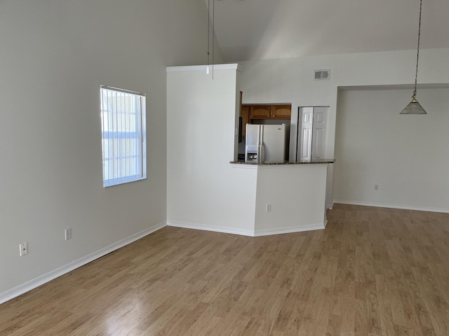 unfurnished living room featuring light hardwood / wood-style flooring and a high ceiling