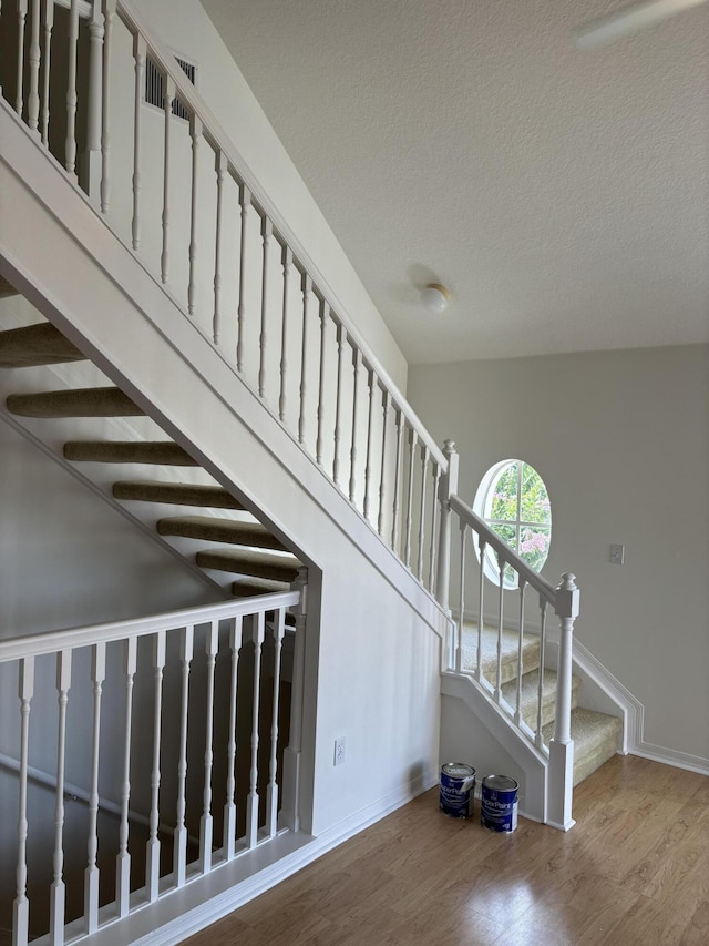 staircase with wood-type flooring and a textured ceiling