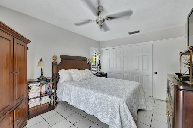 bedroom featuring ceiling fan, a closet, light tile patterned flooring, and a textured ceiling