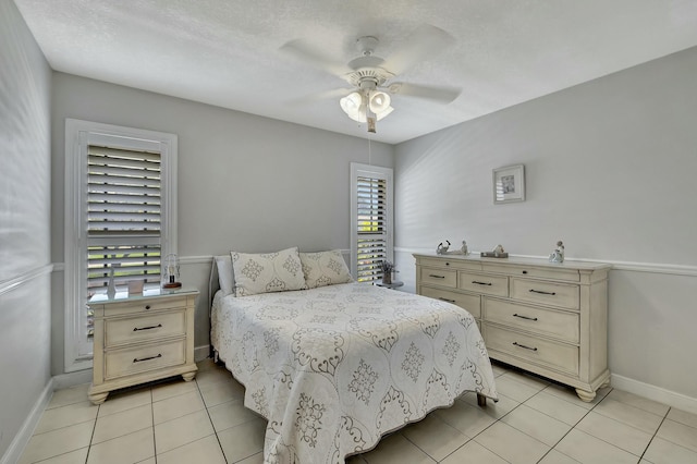 tiled bedroom featuring ceiling fan, a textured ceiling, and multiple windows