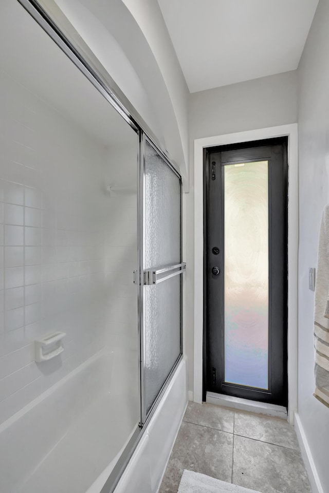 bathroom with tile patterned flooring and bath / shower combo with glass door