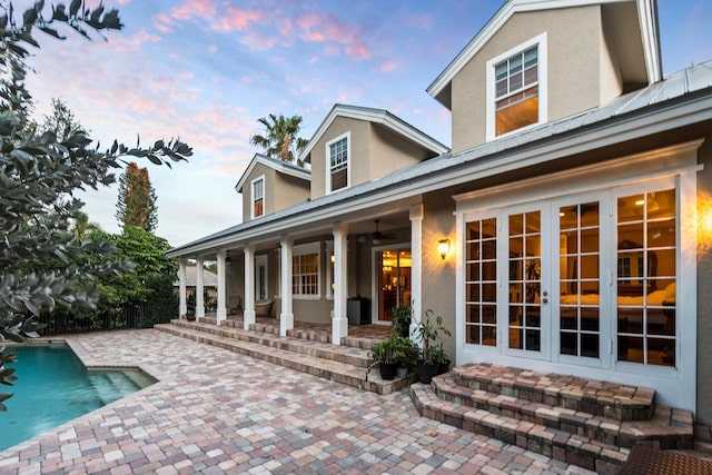 back house at dusk featuring a patio area, ceiling fan, and french doors