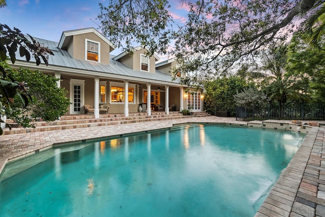 pool at dusk with a patio area