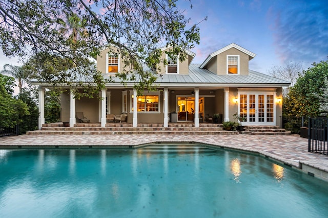 back house at dusk featuring french doors and a patio