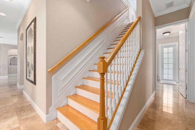 staircase with light tile floors and ornamental molding