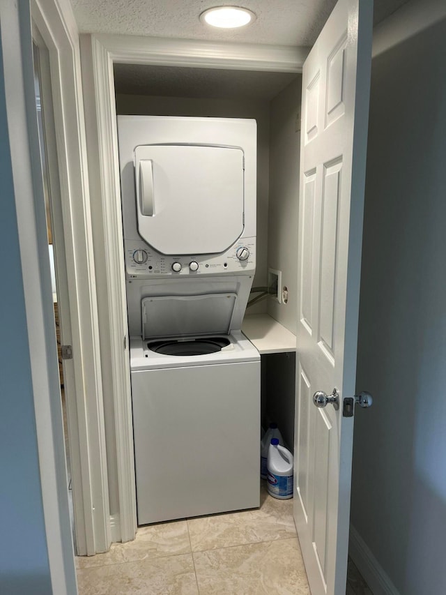 laundry area with stacked washer / drying machine, hookup for a washing machine, and light tile floors