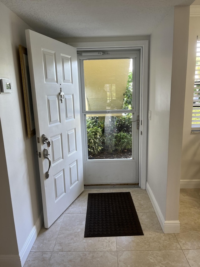 doorway featuring light tile flooring and a textured ceiling