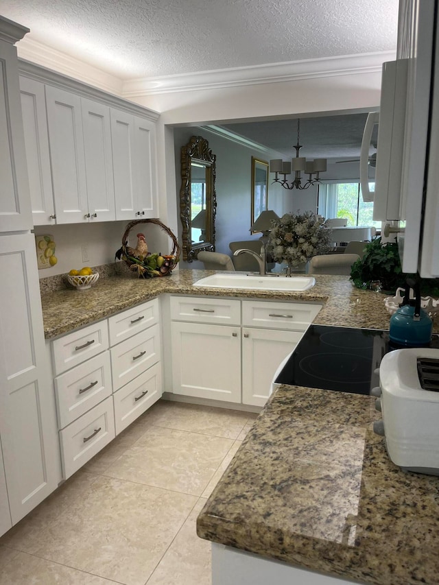 kitchen featuring a notable chandelier, dark stone counters, kitchen peninsula, a textured ceiling, and ornamental molding