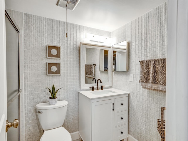 bathroom featuring tile walls, toilet, and vanity