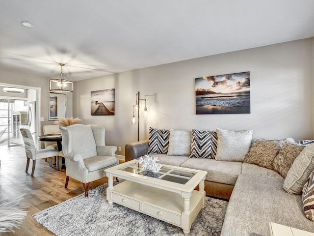 living room with light hardwood / wood-style floors and a notable chandelier