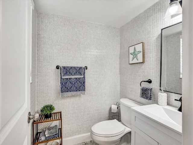 bathroom with tile walls, toilet, and vanity