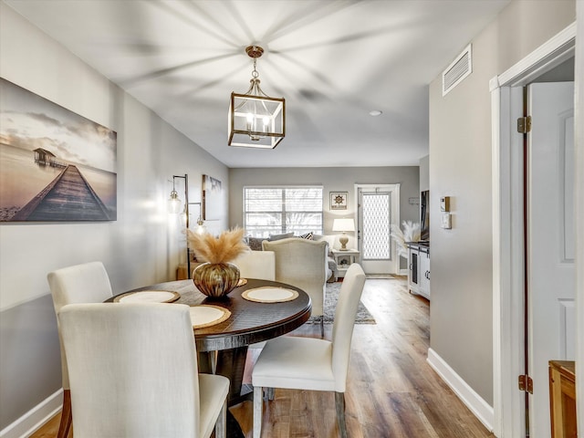 dining area featuring an inviting chandelier and light hardwood / wood-style flooring