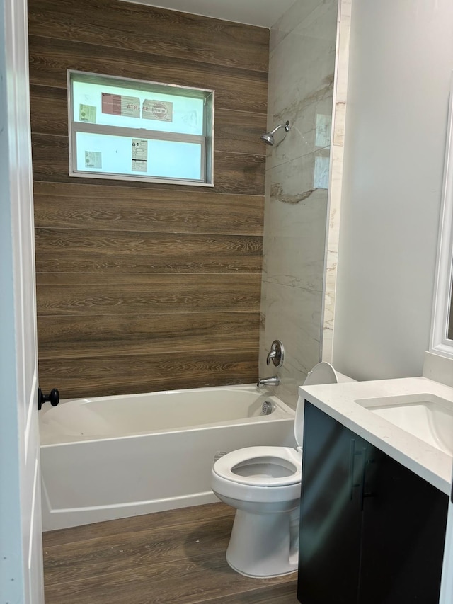 full bathroom featuring vanity, wooden walls, hardwood / wood-style flooring, toilet, and tiled shower / bath