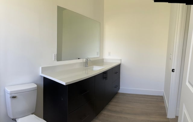 bathroom with hardwood / wood-style floors, vanity, and toilet