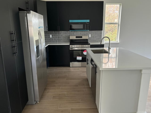 kitchen featuring decorative backsplash, light wood-type flooring, sink, and appliances with stainless steel finishes