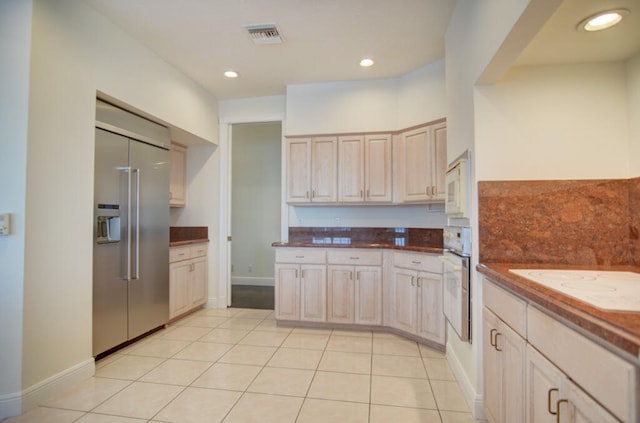 kitchen with built in appliances, light brown cabinetry, and light tile floors