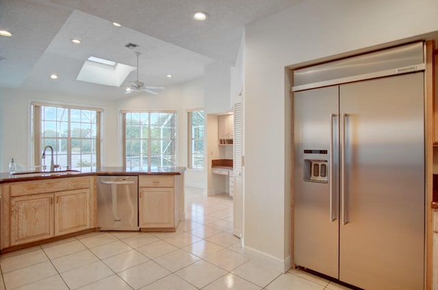 kitchen featuring light tile floors, ceiling fan, appliances with stainless steel finishes, and a skylight