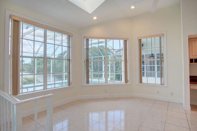 tiled spare room featuring plenty of natural light and vaulted ceiling with skylight