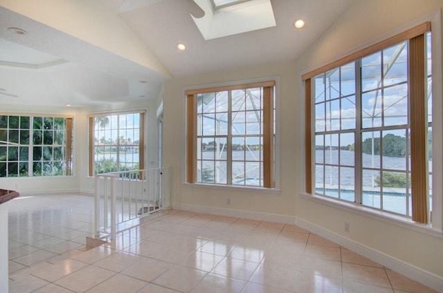 tiled spare room with a water view, vaulted ceiling with skylight, and a wealth of natural light