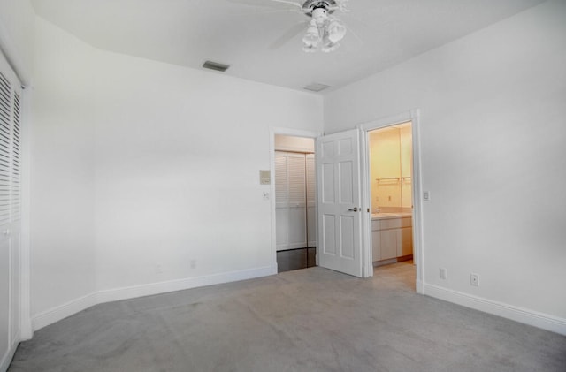 unfurnished bedroom featuring a closet, light carpet, ceiling fan, and connected bathroom