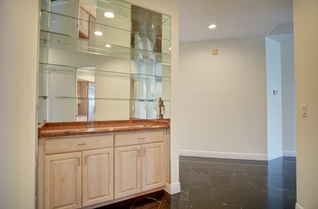 bar with dark tile flooring and light brown cabinetry