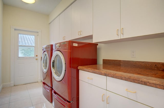 washroom featuring light tile flooring, cabinets, and washing machine and clothes dryer