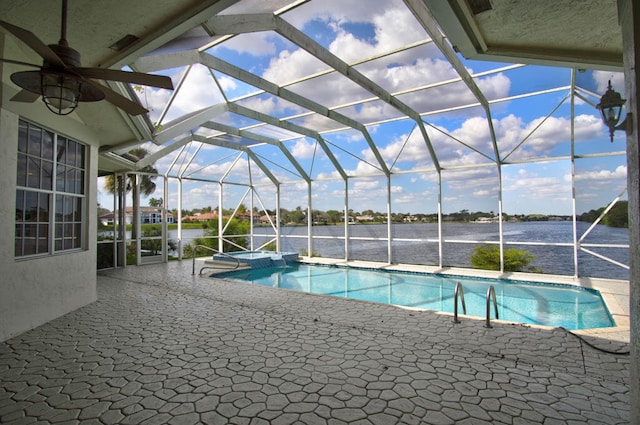 view of pool featuring a water view, a lanai, ceiling fan, and a patio