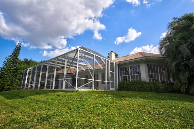 back of house featuring a lanai and a yard