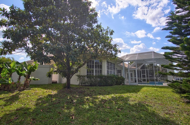 rear view of property with a yard and a lanai