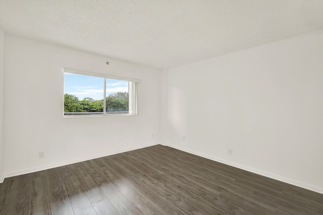 spare room with a textured ceiling and dark hardwood / wood-style flooring