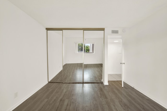 unfurnished bedroom with a closet and dark wood-type flooring