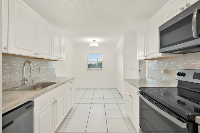 kitchen with tasteful backsplash, stainless steel appliances, white cabinetry, and sink