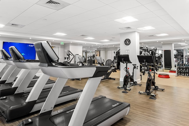 workout area featuring light hardwood / wood-style floors and a drop ceiling