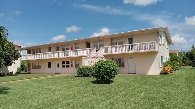 back of house with a lawn and a balcony