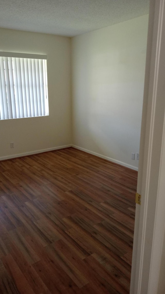 unfurnished room featuring a textured ceiling and dark hardwood / wood-style floors