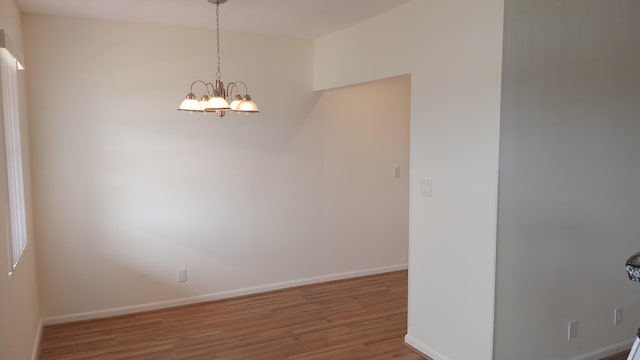 empty room featuring hardwood / wood-style floors and a chandelier