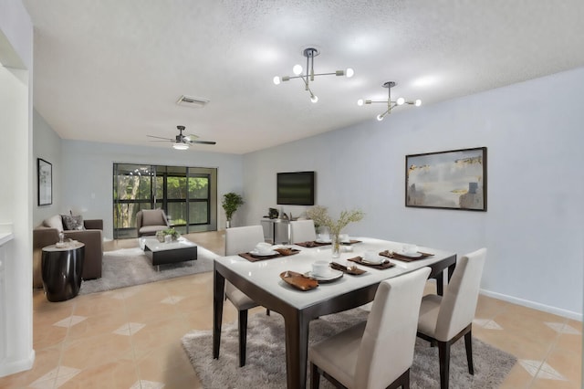 tiled dining area featuring a textured ceiling and ceiling fan with notable chandelier