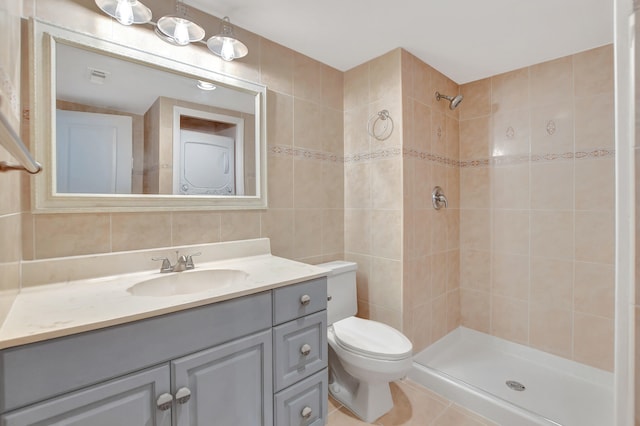 bathroom with vanity, tile patterned floors, tile walls, a tile shower, and toilet