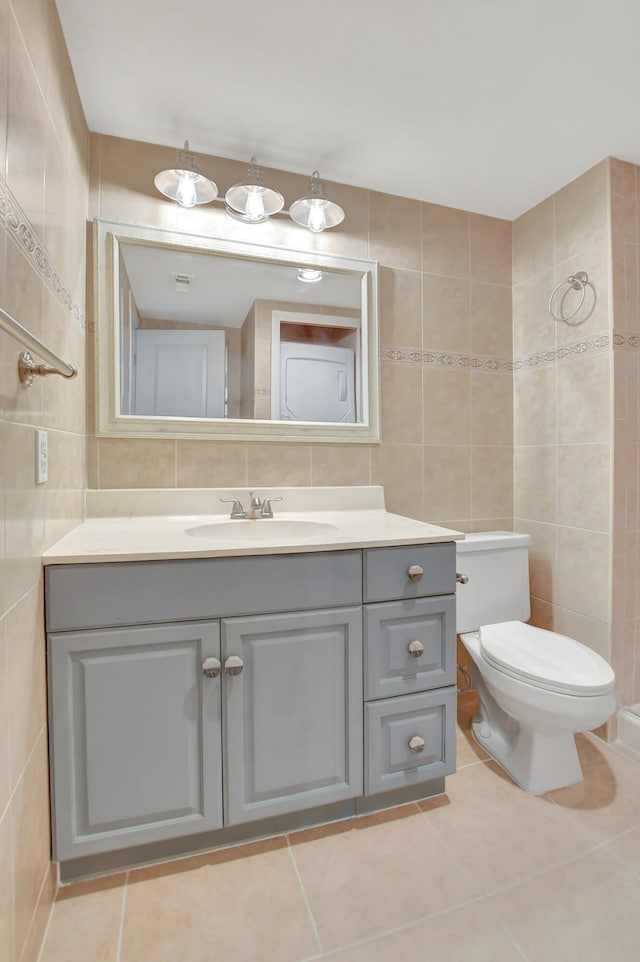 bathroom featuring vanity, tile patterned floors, tile walls, toilet, and backsplash