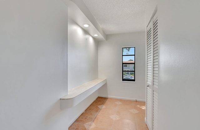 hallway with light tile patterned floors and a textured ceiling