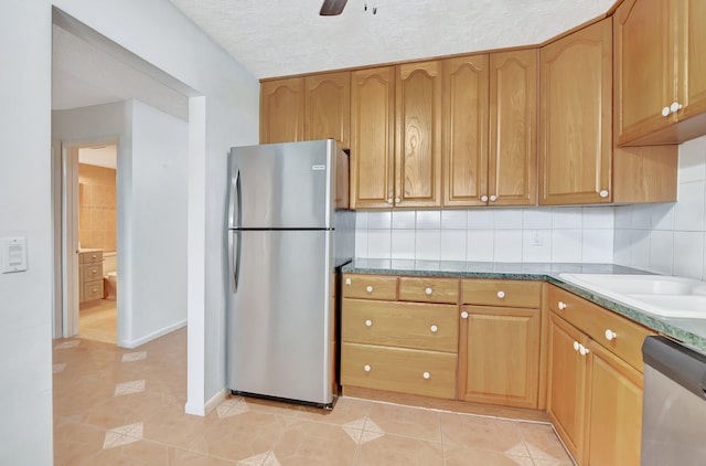 kitchen featuring appliances with stainless steel finishes, light tile patterned floors, a textured ceiling, and tasteful backsplash