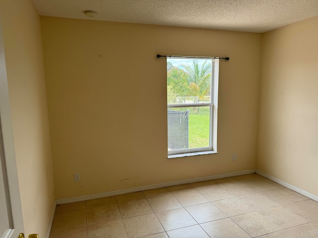 tiled empty room with a textured ceiling