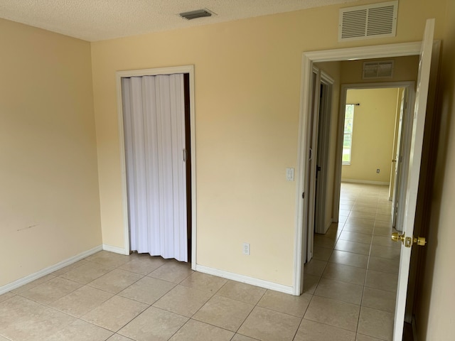 unfurnished bedroom with a closet, a textured ceiling, and light tile flooring