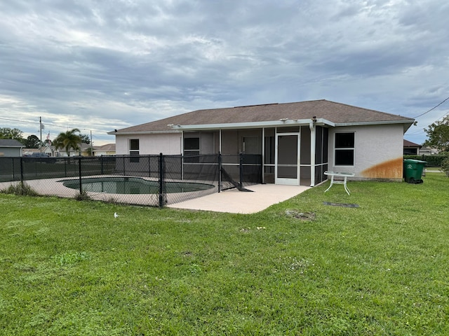 back of property with a fenced in pool, a lawn, and a patio