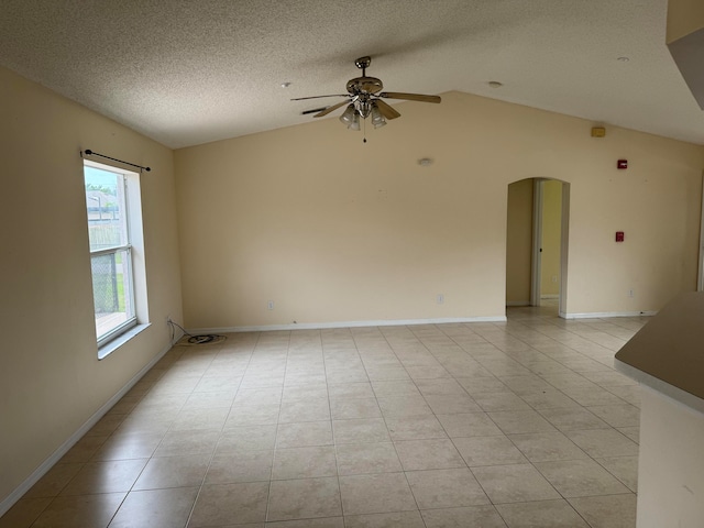 spare room featuring lofted ceiling, a textured ceiling, ceiling fan, and light tile flooring