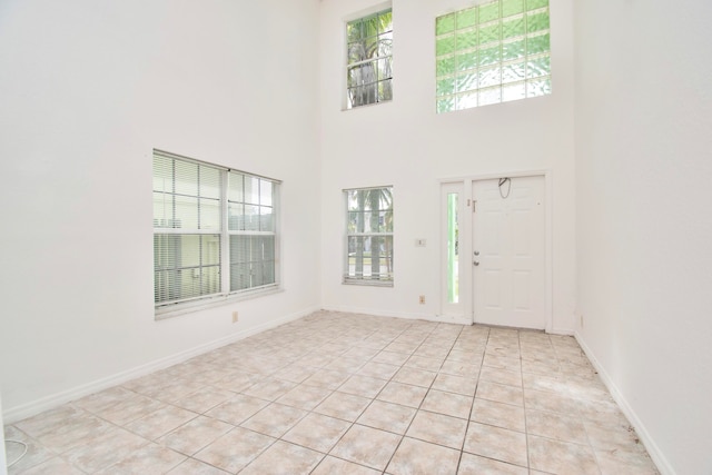 entryway with light tile floors, a towering ceiling, and a wealth of natural light