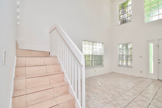 stairway with a healthy amount of sunlight, light tile floors, and a high ceiling