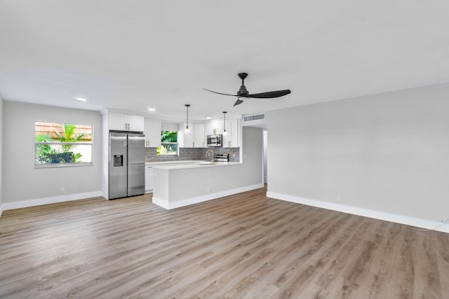 unfurnished living room featuring ceiling fan, light wood-type flooring, and sink