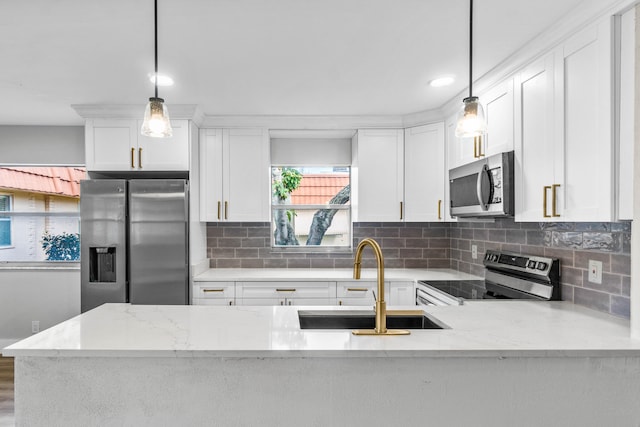 kitchen with light stone counters, white cabinets, stainless steel appliances, and decorative light fixtures