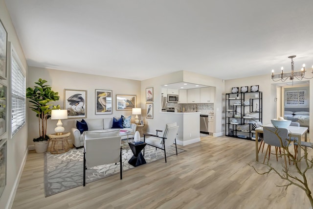 living room with light hardwood / wood-style floors and a notable chandelier